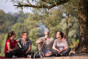 Freunde, die Wasserpfeife am Flussufer rauchen foto