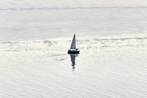 Yacht mit weißen Segelsegeln in der Bucht in der Abenddämmerung foto