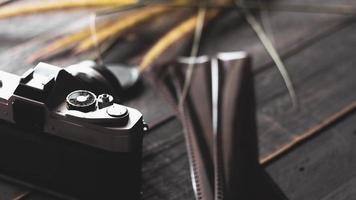 Retro-Filmkamera und Negativfilm auf einem schwarzen Holztisch foto