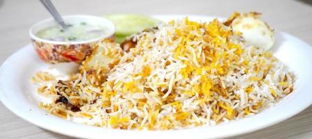 spezielles Kolkata Chicken Biryani, serviert mit Raita foto