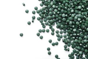 Vegetarische Vitamine aus Spirulina sind auf weißem Hintergrund verstreut foto