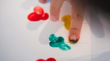 Die kleinen Finger der Kinder schaffen Kunst mit Wasserfarben. Kind tauchte seinen Finger in Farbe und klebte ihn auf weißes Papier seiner Fantasie. kinder hobbys. foto