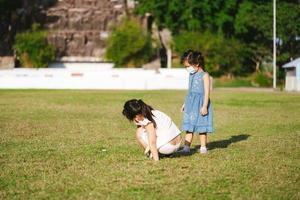 Porträtbild Kind 5-6 Jahre alt. Kinder spielen auf dem Rasen. Kinder interessieren sich für kleine Insekten, die auf grünem Gras sitzen. Sommer oder Frühling. kindergartenmädchen tragen gesichtsmaske, um pm2.5 staub zu verhindern foto
