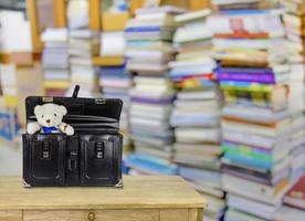 Schwarze Schultasche aus Retro-Leder mit Teddybär, Bibliothek unscharfer Hintergrund foto