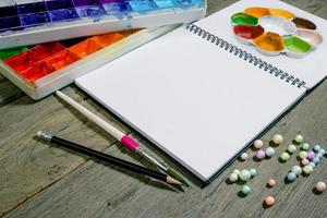 Nahaufnahme offenes Notizbuch mit Tablettfarben auf Holzhintergrund foto