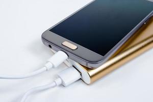 Goldene Powerbank mit Smartphone im Hintergrund foto