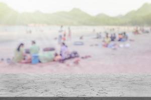 Marmortisch mit vielen Menschen am Strand verschwommenen Hintergrund foto