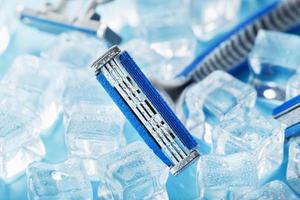 blaue Rasiermaschine mit scharfen Klingen auf dem Hintergrund von Eiswürfeln aus nächster Nähe foto
