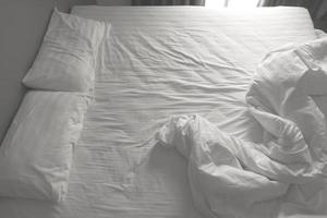 unordentliche weiße Bettwäsche und Kissen. Schwarz-Weiß-Ton foto