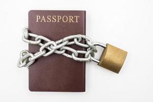Reisepass mit Kette und Vorhängeschloss auf weißem Hintergrund, Konzept der illegalen Einwanderung foto