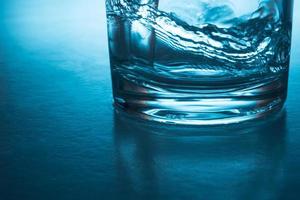 Gießen von Wasser in Glas auf blauem Hintergrund. foto