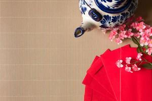 Draufsicht auf chinesische Pflaumenblüten mit roten Päckchen und Teekanne auf dem Tisch, chinesisches Neujahrskonzept, freier Platz für Text foto