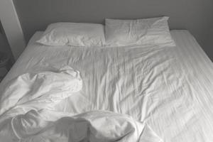 unordentliche weiße Bettwäsche und Kissen. Schwarz-Weiß-Ton foto