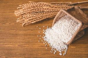 Nahaufnahme von rohem Reis im Leinensack auf Holztisch. foto