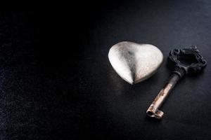 Metallherz mit Schlüssel auf dunklem Hintergrund, Metapher-Liebeskonzept. foto