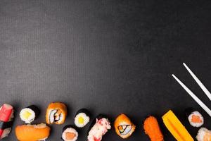 Draufsicht auf Sushi-Set und Essstäbchen auf schwarzem Hintergrund, japanisches Essen. Freiraum für Text foto