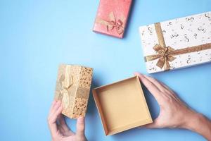 Draufsicht auf männliche Hände, die eine Geschenkbox öffnen, Geschenke auf blauem Hintergrund. foto