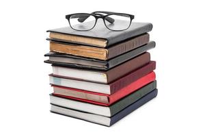 ein Stapel Bücher mit Brille auf weißem Hintergrund. foto