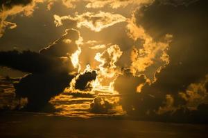 Wunderschöner Sonnenuntergang - das orangefarbene Licht der Sonne durch die Wolken foto