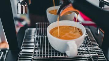Nahaufnahme des Espressos, der aus der Kaffeemaschine fließt und in die Kaffeetasse fließt. Kaffee für Kunden im Café zubereiten. foto