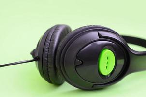 Konzept zum Musikhören. Schwarze Kopfhörer liegen auf grünem Hintergrund foto