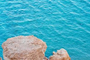 Blick von der Felsenklippe auf das türkisfarbene Wasser des Meeres foto