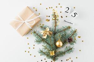 weihnachtsbaum verziert mit goldenen kugeln und geschenkbox auf weißem hintergrund foto
