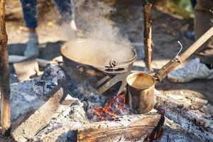 Nahaufnahme des kochenden Topfes am Lagerfeuer beim Picknick. Wanderkochkonzept foto