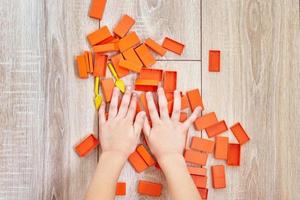 Draufsicht auf Kinderhände, die mit orangefarbenen Spielzeugsteinen spielen foto