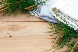 Weihnachten Flatlay auf einem rustikalen hölzernen Hintergrund Grüne Tannennadeln mit Zapfen, warme Wollsachen in Weiß und Blau. neujahrskonzept, winterferienhauskomfort. Platz für Text foto