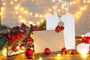 Umschlag aus Kraftpapier mit Glückwünschen und Einladung zu Weihnachten und Neujahr in festlichem Dekor, Lichterketten. Brief für den Weihnachtsmann. Attrappe, natürliches Dekor, handgefertigt. Platz kopieren foto
