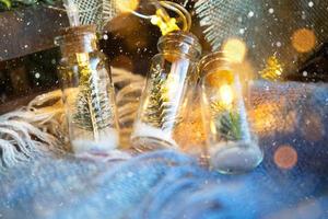 Lichterketten in einem Glas mit Weihnachtsbaum und Schnee in Nahaufnahme auf einem warmen, gemütlichen Plaid mit Holzdekor. weihnachten und neujahr, festliche dekoration, wohnlichkeit zu hause, vorbereitung auf feier, fabelhafte stimmung foto