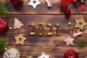 weihnachtswohnung lag mit neujahr 2021 symbol der goldenen zahlen in der mitte. Urlaubsatmosphäre, Holzsterne, Spielzeug, Perlen, rote Kugeln, Fichtenzweige auf dunklem Hintergrund. Platz für Text
