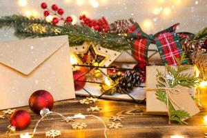 Umschlag aus Kraftpapier mit Glückwünschen und Einladung zu Weihnachten und Neujahr in festlichem Dekor, Lichterketten. Brief für den Weihnachtsmann. Attrappe, natürliches Dekor, handgefertigt. Platz kopieren foto