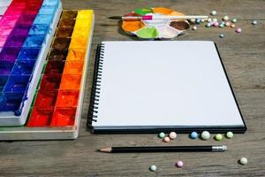 Nahaufnahme offenes Notizbuch mit Tablettfarben auf Holzhintergrund foto