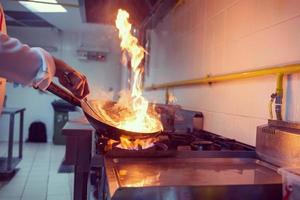 Koch macht Flamme auf Essen foto