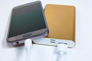 Goldene Powerbank mit Smartphone im Hintergrund foto