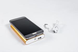 Goldene Powerbank mit Smartphone im Hintergrund foto