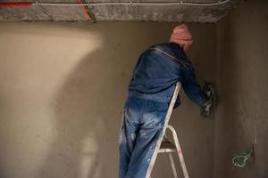 arbeiter, der die wand mit beton verputzt foto