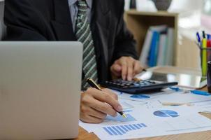 Geschäftsmann hält Stift Dokument Diagramm Buchhaltung Finanzen Papier Arbeit Analyse Diagramm Marketing Investitionen und Bericht Wirtschaft mit Computer Laptop auf dem Schreibtisch im Büro. foto