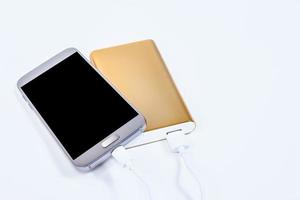 Goldene Powerbank mit Smartphone im Hintergrund foto