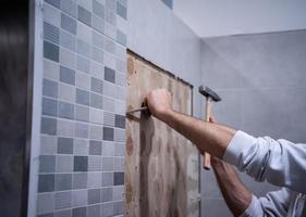 Arbeiter entfernen alte Fliesen in einem Badezimmer abreißen foto