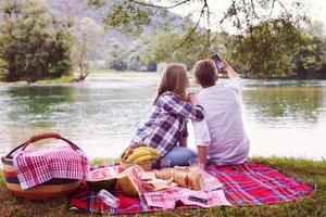 Paar, das ein Selfie mit dem Handy macht, während es die Picknickzeit genießt foto