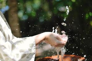 frisches Wasser auf die Hände der Frau spritzen foto