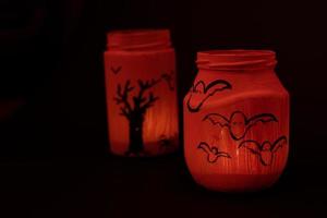 handgemaltes glas für halloween, glas in orange farbe auf schwarzem hintergrund. foto