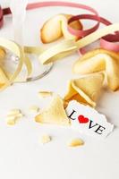 Kekse in Form von Tortellini mit dem Wort Liebe auf Papier und ein Glas Champagner mit Luftschlangen. vertikales Bild. foto