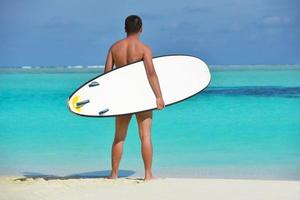 Mann mit Surfbrett am Strand foto