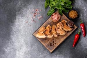 Gebackene Hähnchenflügel mit Sesam und Sauce auf einem Holzbrett foto