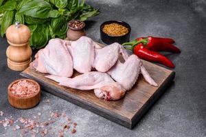 rohe Hühnerflügel mit Zutaten zum Kochen auf einem Holzschneidebrett