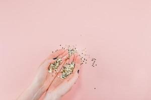 frauenhände bedeckten goldene sterne konfetti auf rosa foto